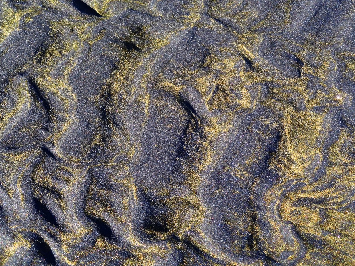 Some of the New Zealand beaches are black volcanic ash, with bright shiny dots, purples and golds ...